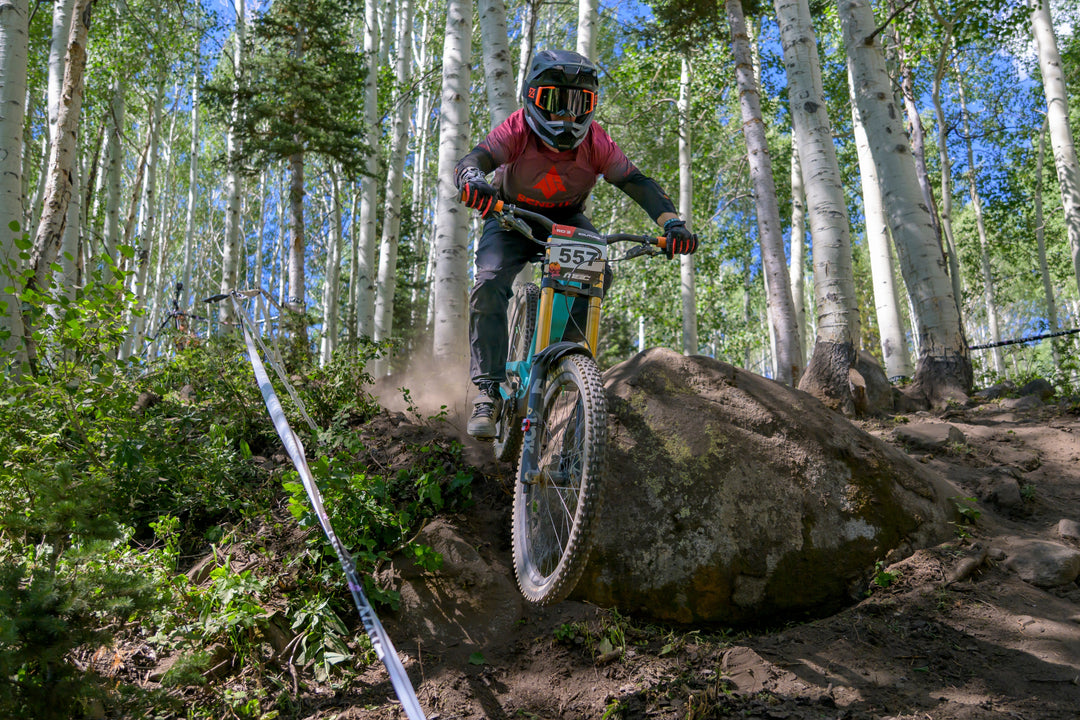 SEND IT mountain bike racer descending through an aspen forest